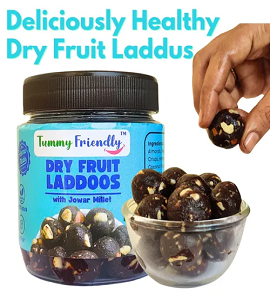 Jar of dry fruit laddus with a bowl of laddus and a hand holding one, labeled 'Deliciously Healthy Dry Fruit Laddus'.